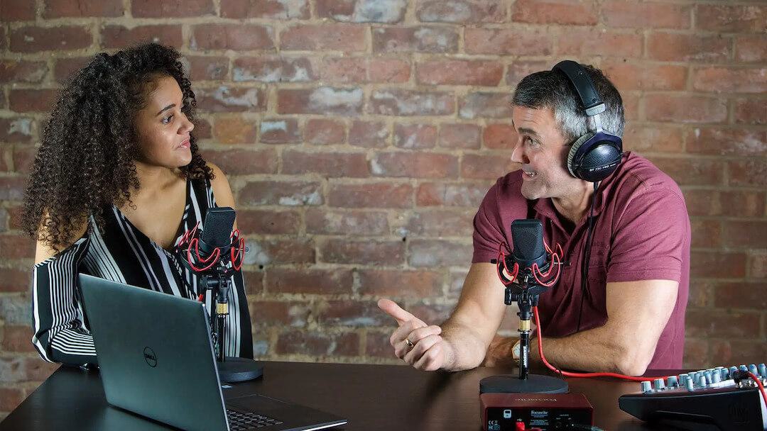 Image shows a man and woman conducting a radio interview.