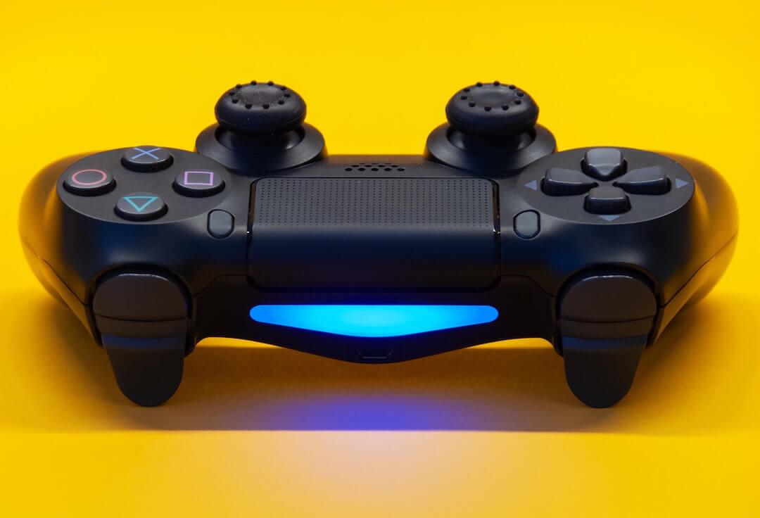 Image shows a playstation controller against a yellow background.