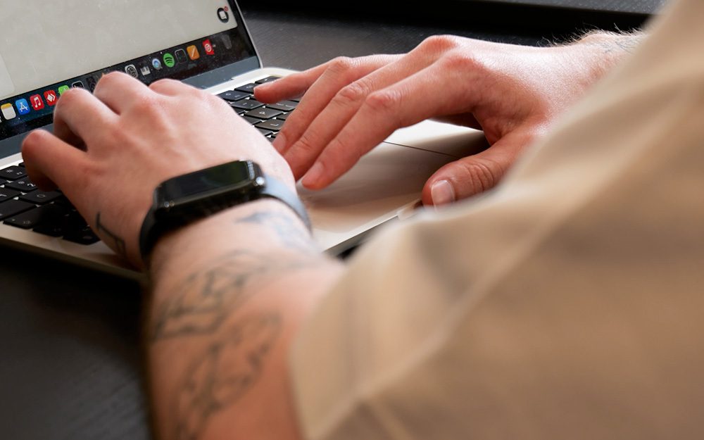 Image shows a close up of someone typing on a laptop.