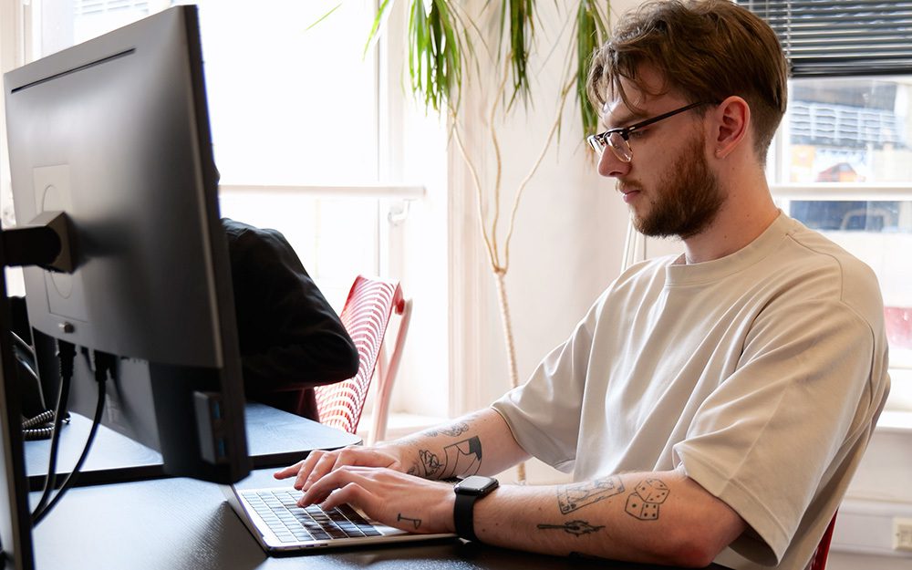 Image shows a man at a computer in an office.