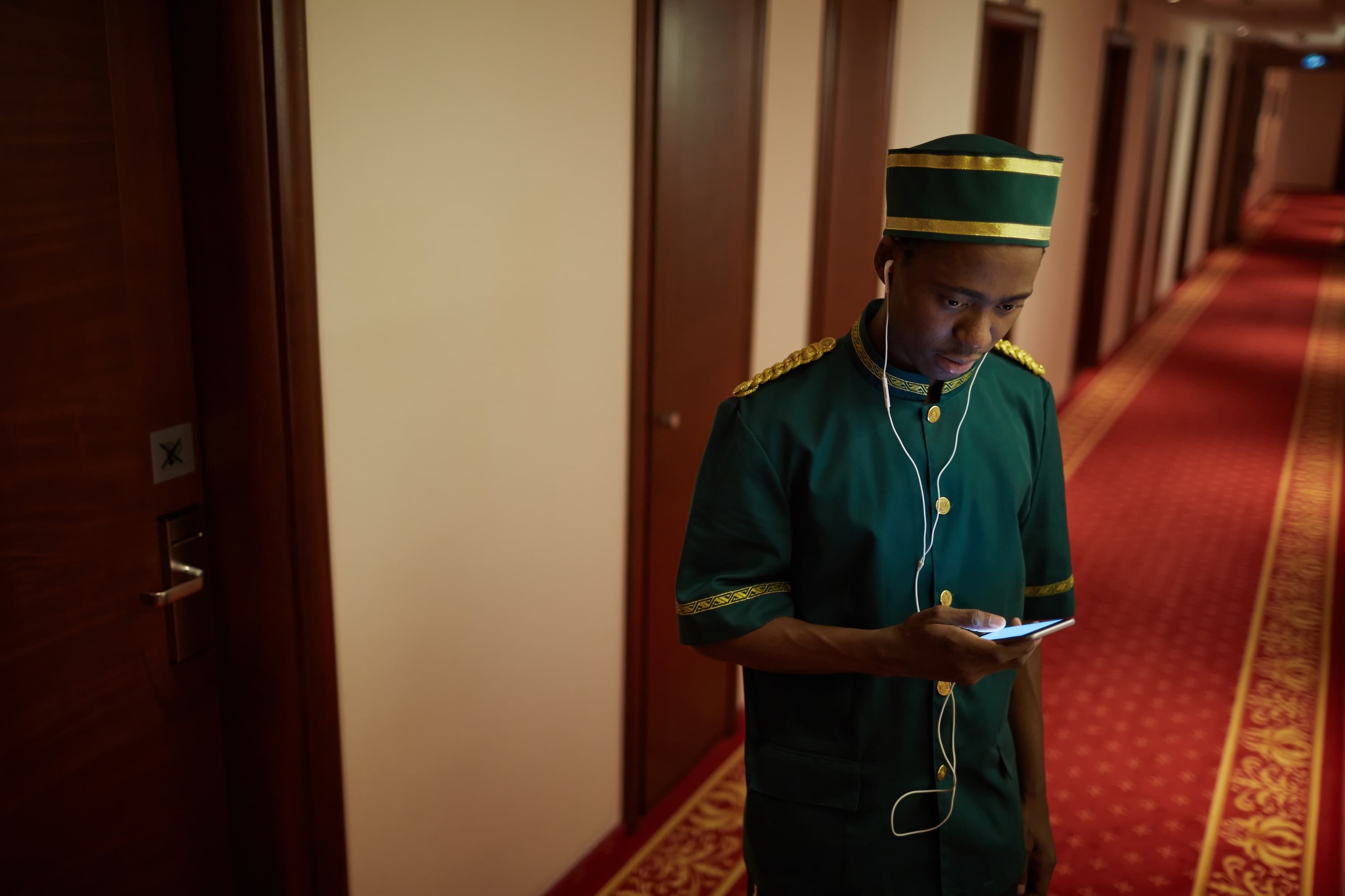 Bellboy listening to music through earphones in hotel hall