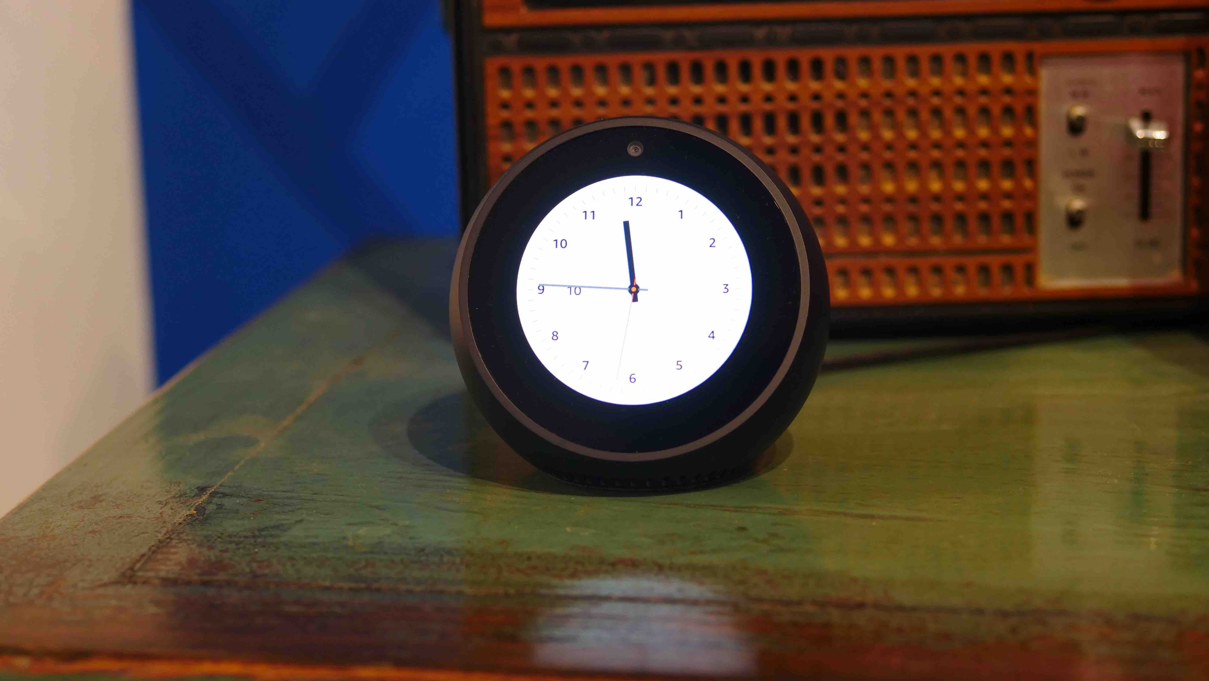 Image shows a small light up clock on a chest of drawers, with an old radio behind it.