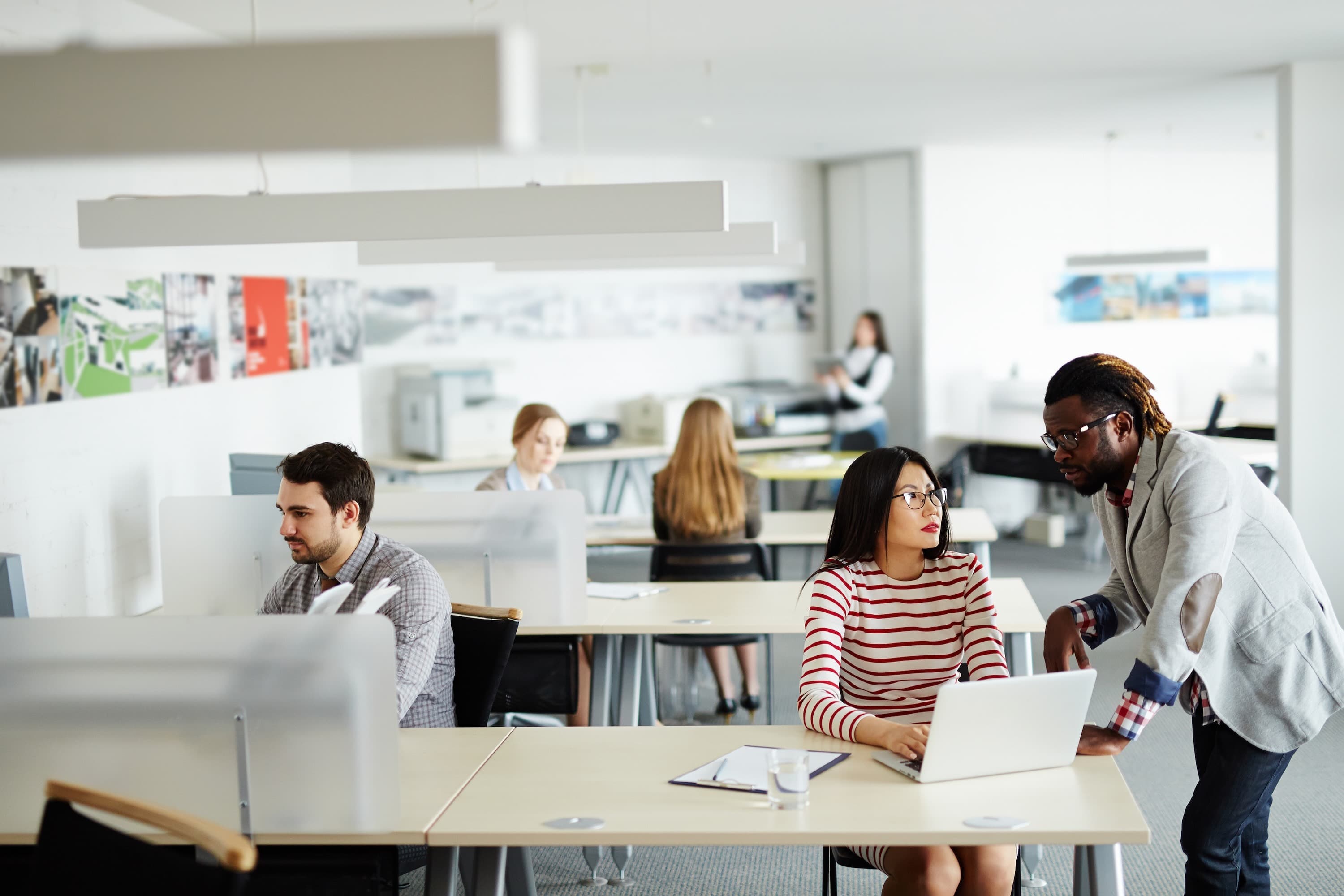 Busy open plan office space with employees working and chatting.