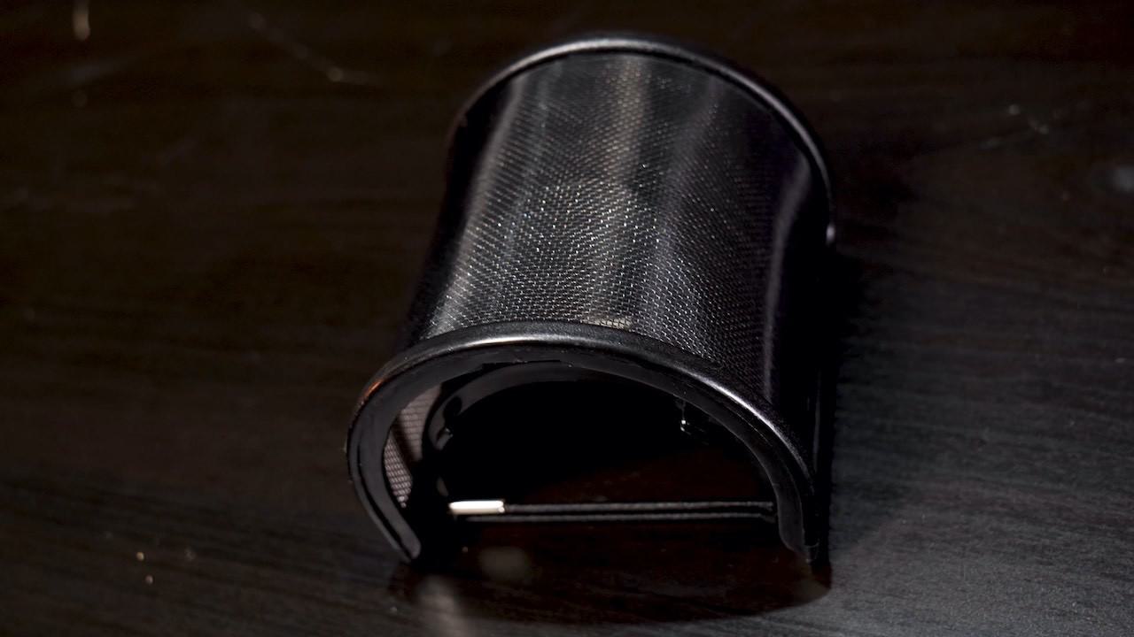 this is a plain black background with a Pop filter in the centre of the image, a rounded sort of grid appearing piece of equipment.