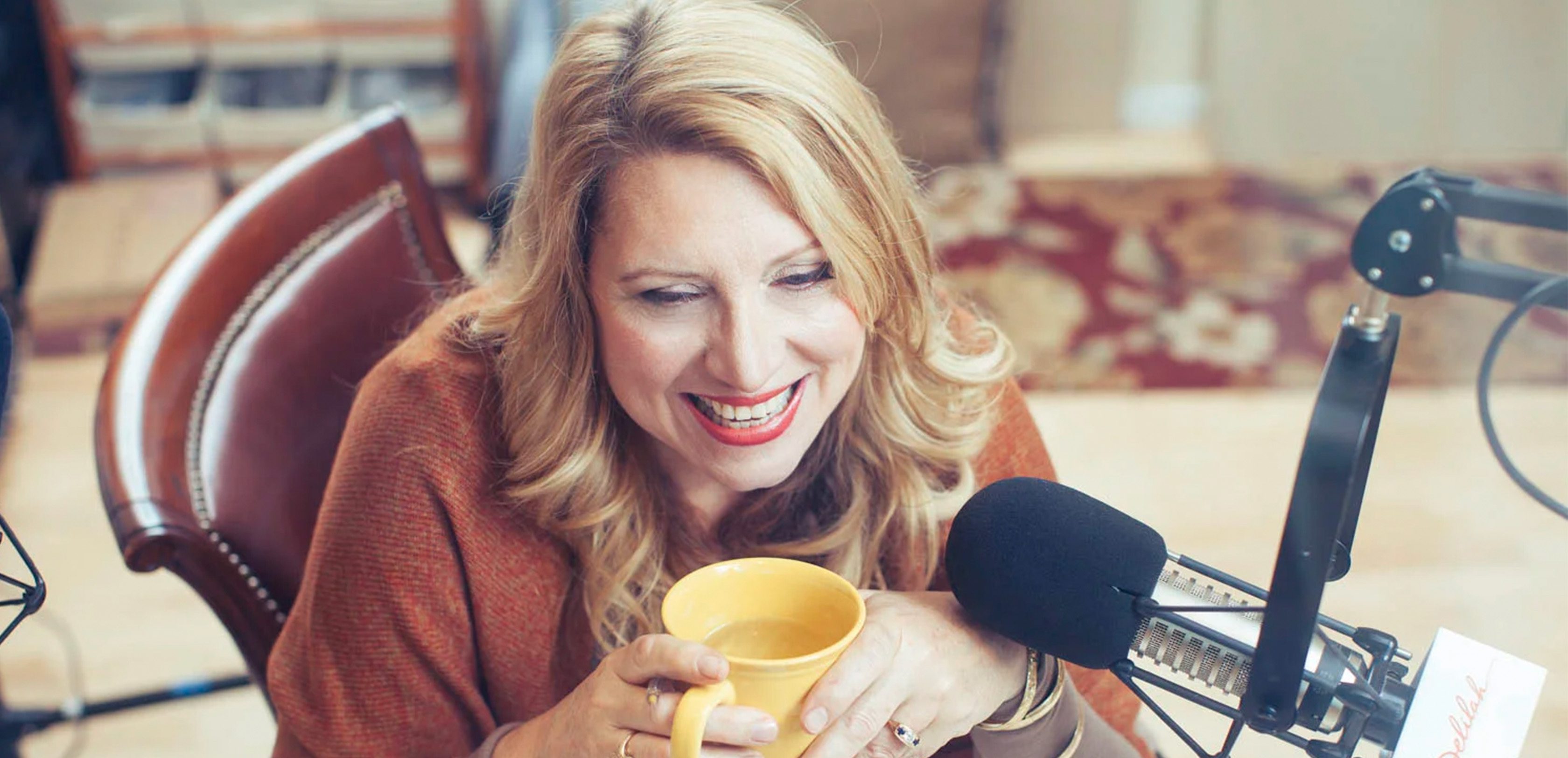 Radio Host, Delilah, drinking tea and smiling behind a microphone.