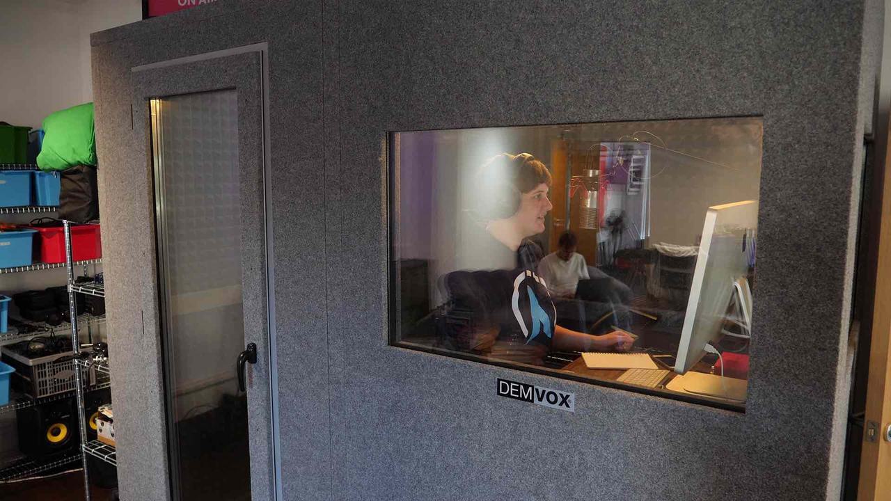 Image shows a person broadcasting within a purpose-built sound booth