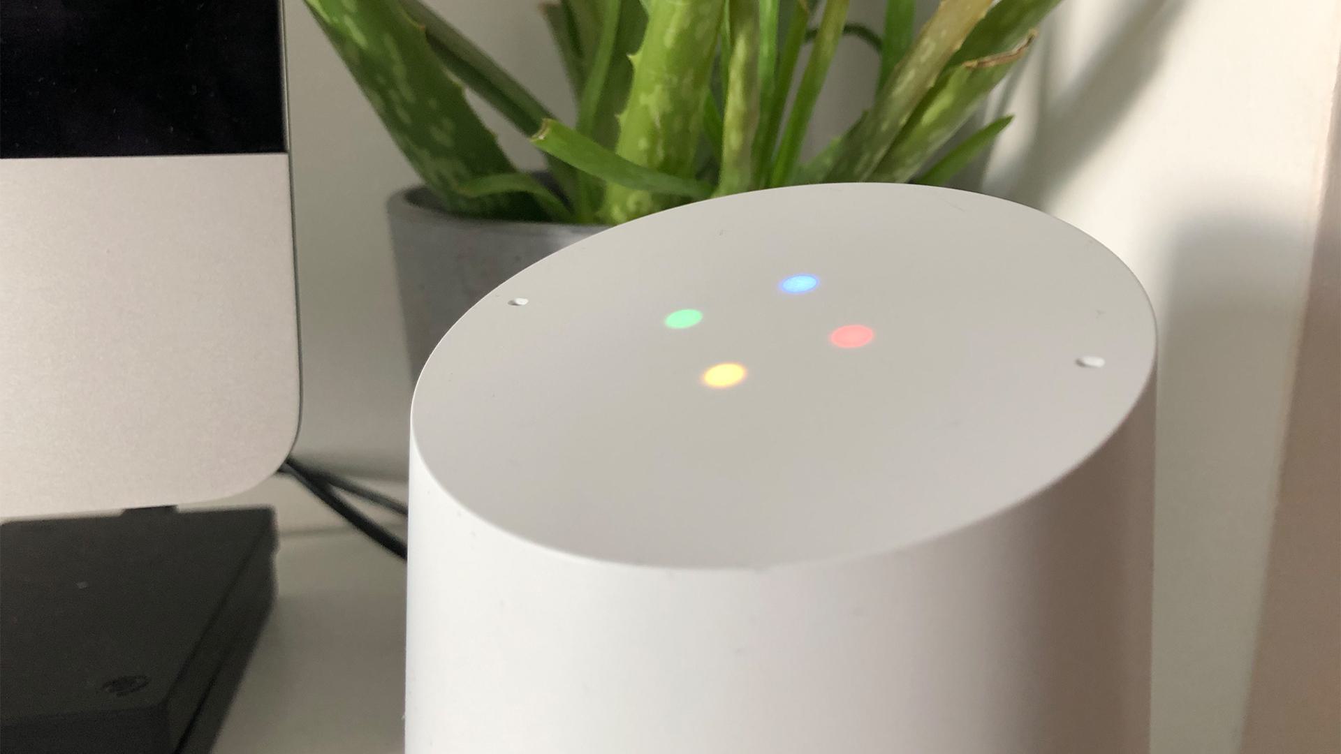 Image shows a close up of a Google Home smart speaker, with all 4 display lights on.