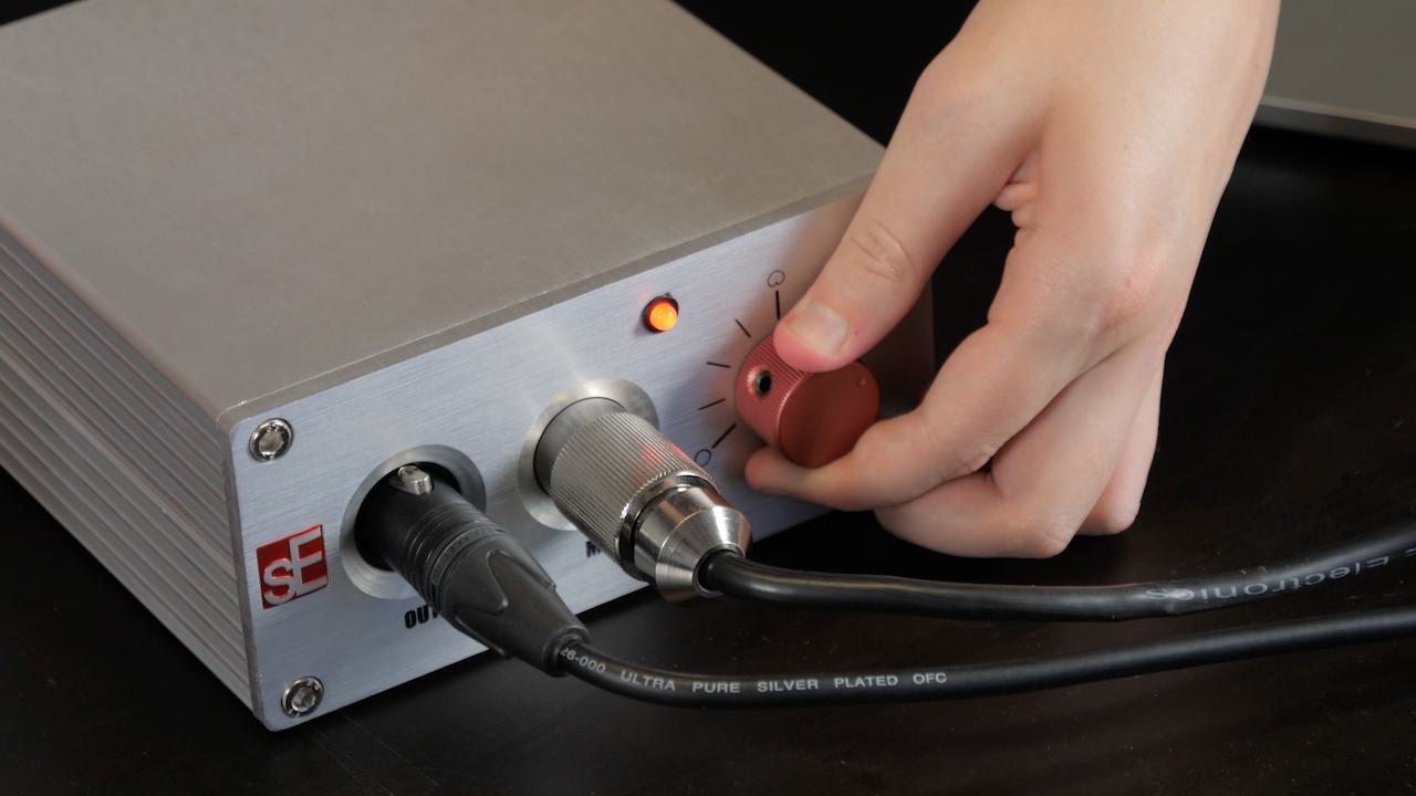 Image shows someone adjusting a dial on the sE Electronics Z56000A II power supply box.