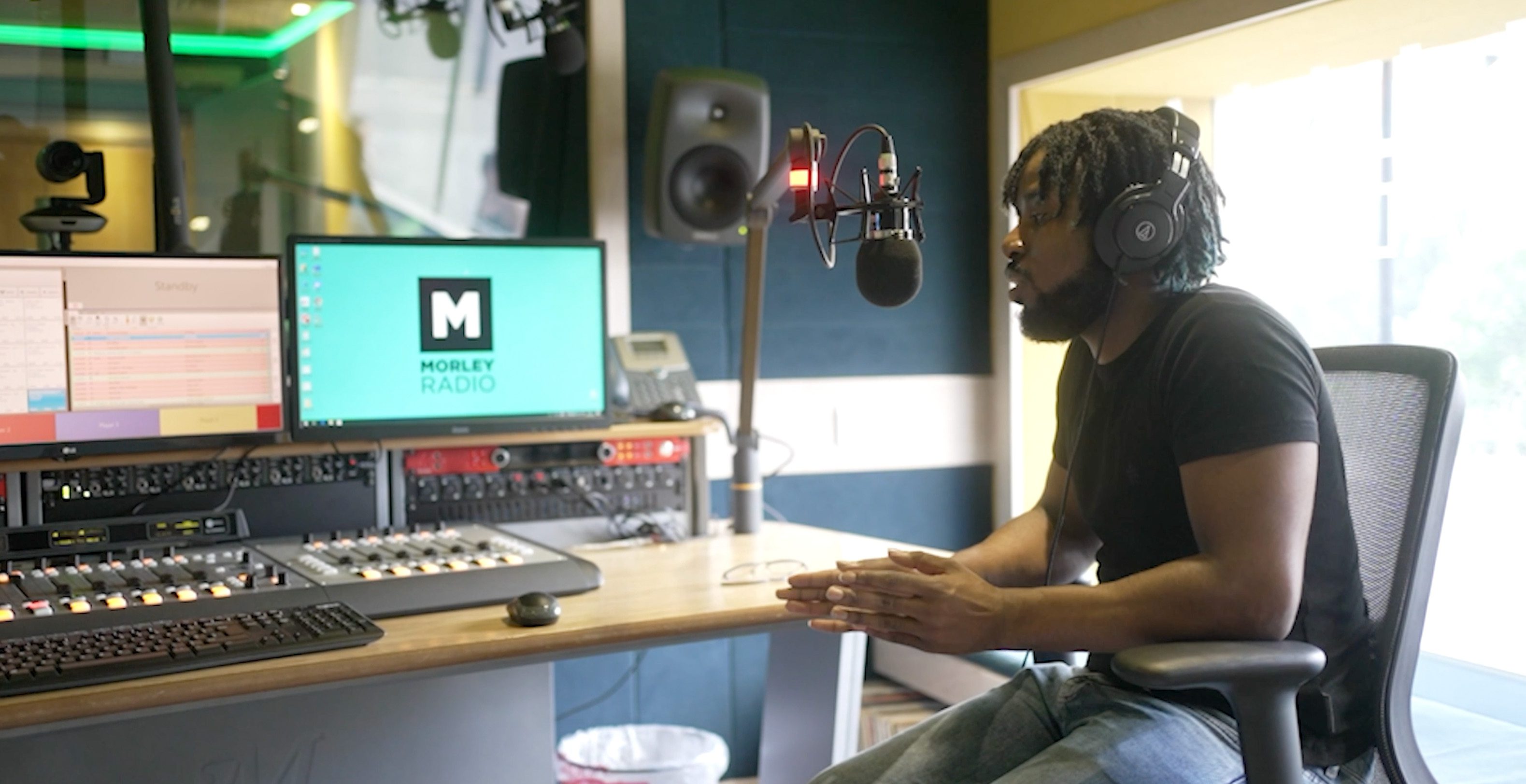 A man talking into a mic and broadcasting in a radio studio.