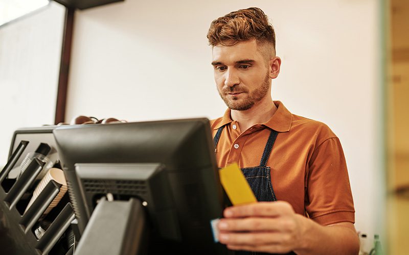 A cashier processing an order in a coffee shop.
