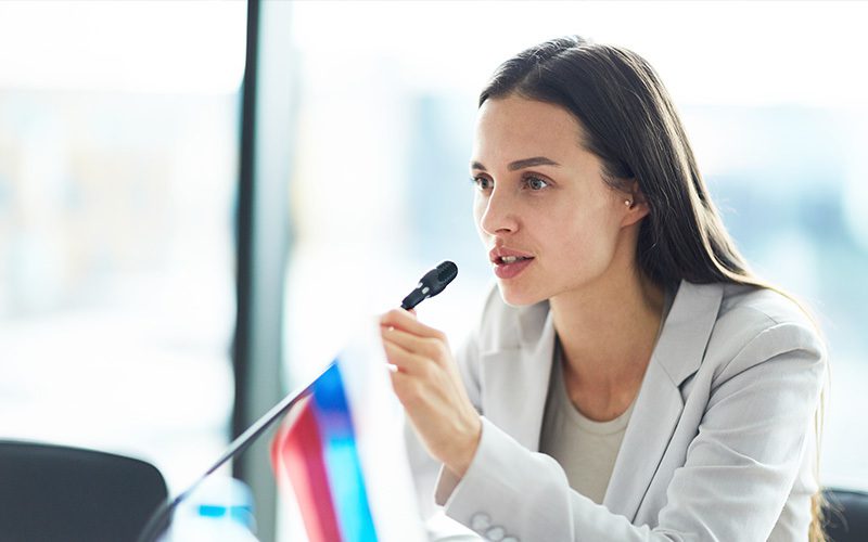 A professional woman talking in to a microphone.