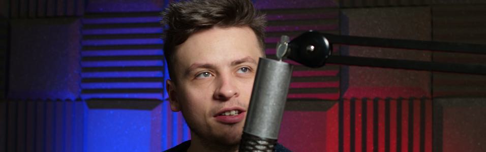 Image shows a young man behind a microphone in a soundproofed room.