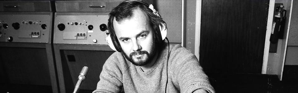 Image shows a black and white photo of a young John Peel in a radio booth.