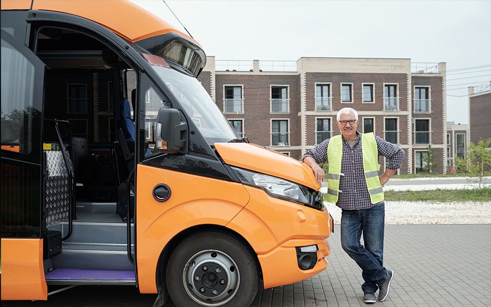 Image shows a bus driver leaning on his bus.