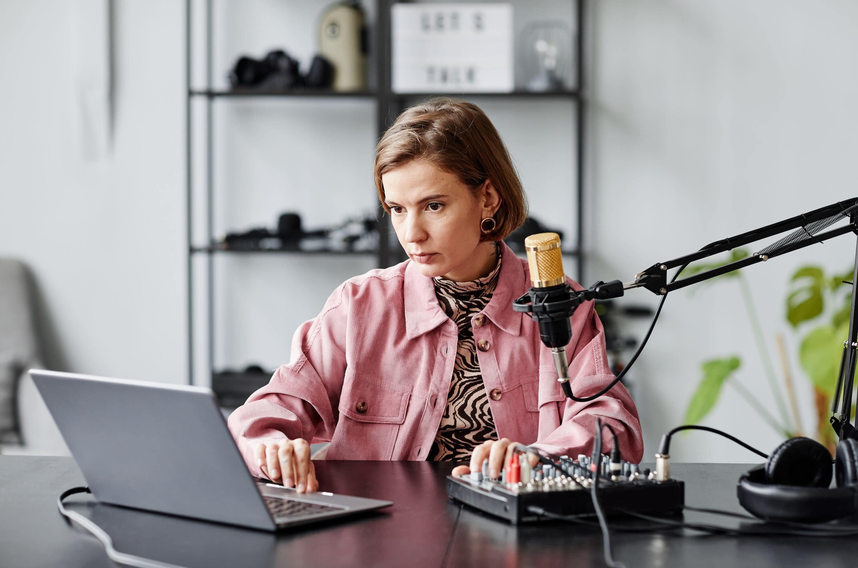 Woman Using Laptop And Setting Up Equipment For Radio Show