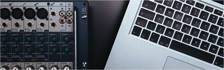 This is an image of a black sound mixer on the left. On the right touching it are the keys of a Macbook, black contrasting onto a silver back.