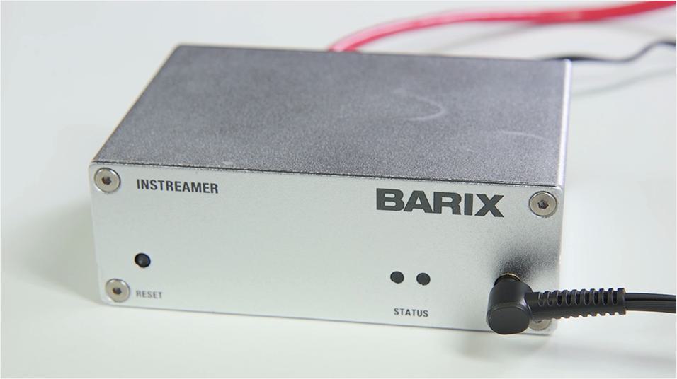 This is an image of the Barix Instreamer, a grey box with a cable plugged in and the word Barix emblazoned across it. It is on a white, neutral background.