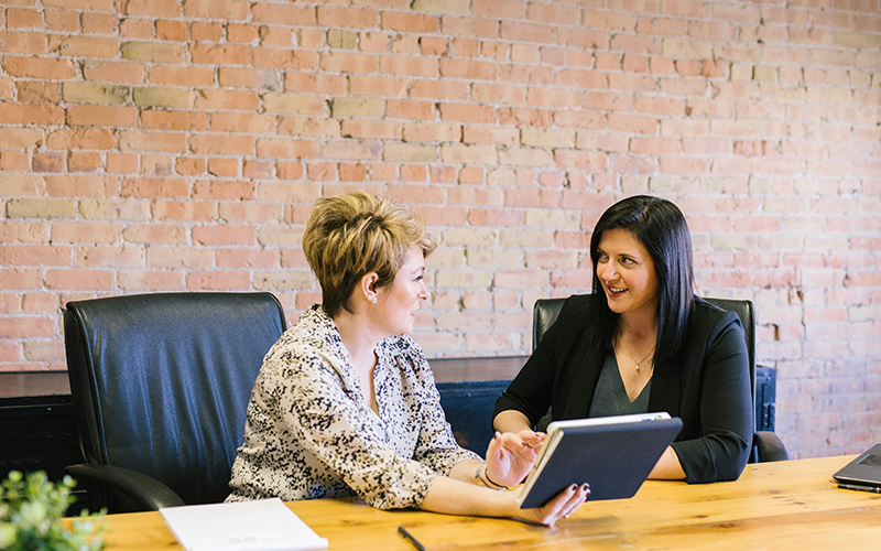 Image shows two women having a meeting within an office.