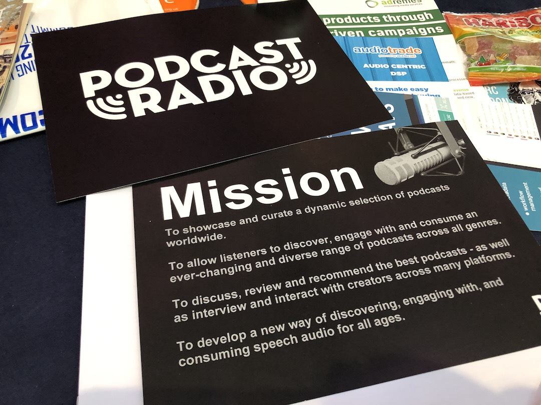 Image shows some Podcast Radio leaflets on a desk, including one that has their mission statement on it.