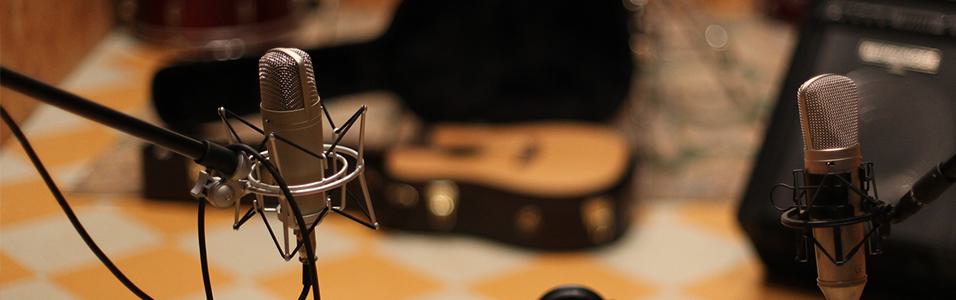 This is an image of two microphones against a yellow and white backdrop. Both are silver.