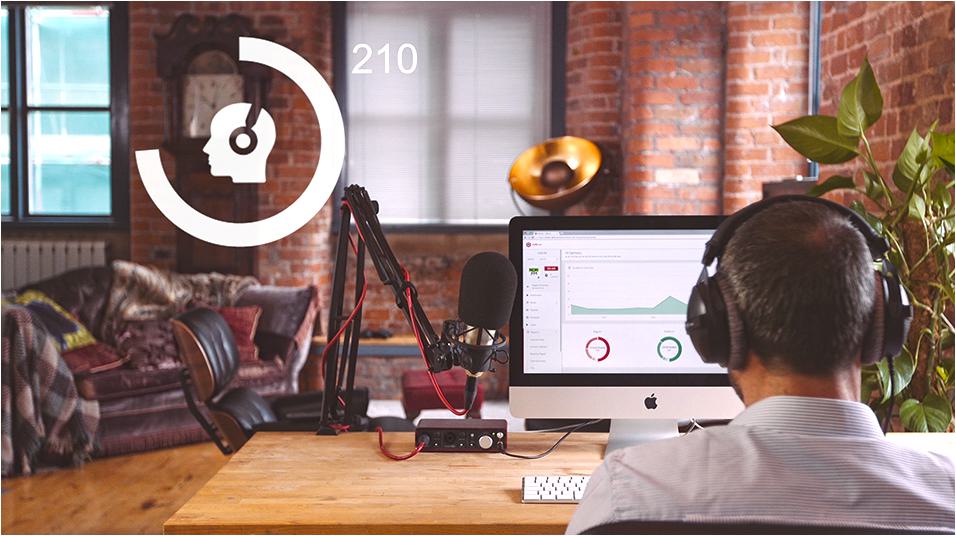 This is a warmly lit image of a home studio, with a man wearing headphones sat at a Macbook in the forefront of the shot. There is a white circular webinar logo in the left hand side.