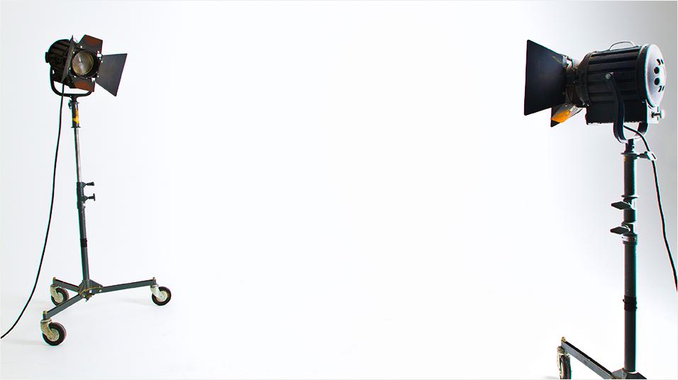 There is a white backdrop. On the left is a black stage light, on the right is another, pointing at one another.