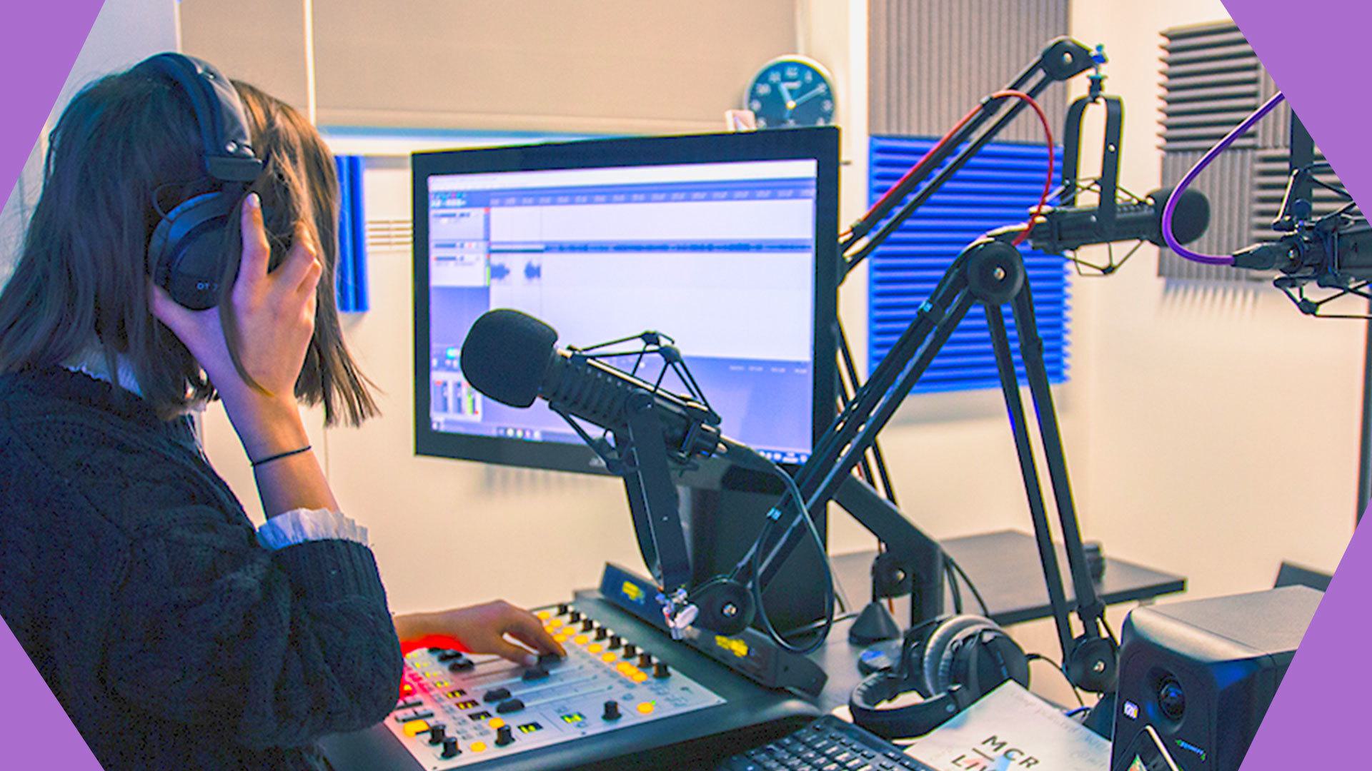 This is a side on image of a white person with their hands, hair and headphones covering their face. They talk in front of a black microphone, and a blue and grey monitor. The borders to this image are purple.