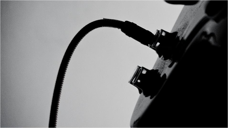 This is a black and white image of a wire and small input into a mixing desk but a very zoomed image, so that all is visible really is the wire.