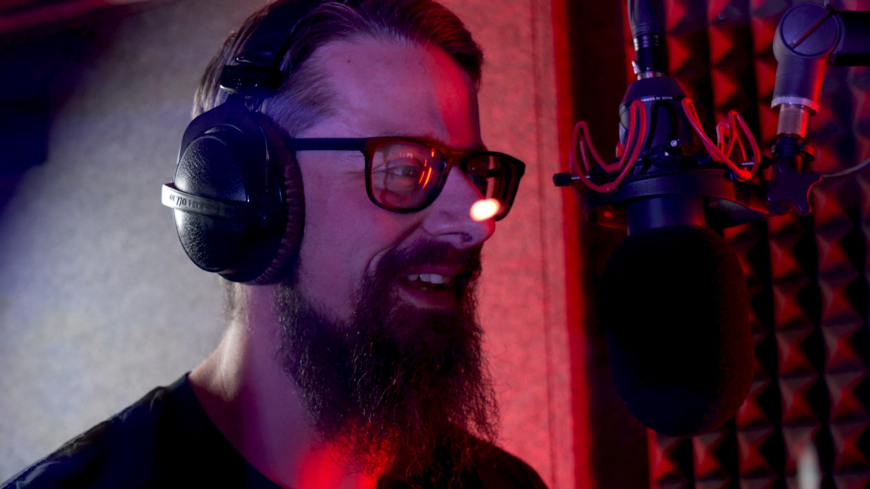 Radio presenter talking on microphone inside studio sound booth