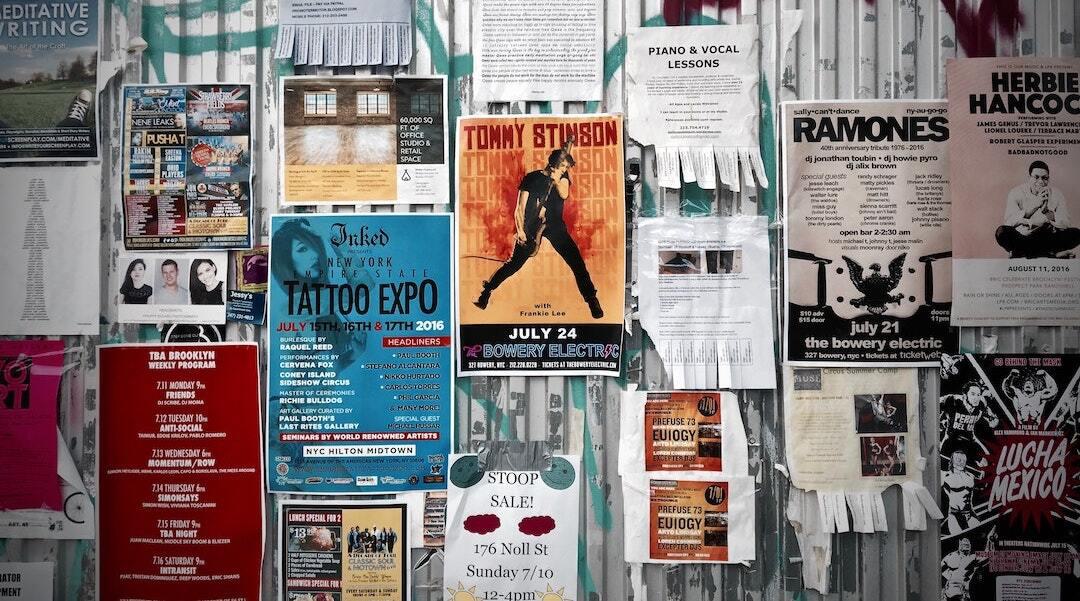 This is a picture of a heavily postered/flyered wall. There are posters of all different colours and covers.