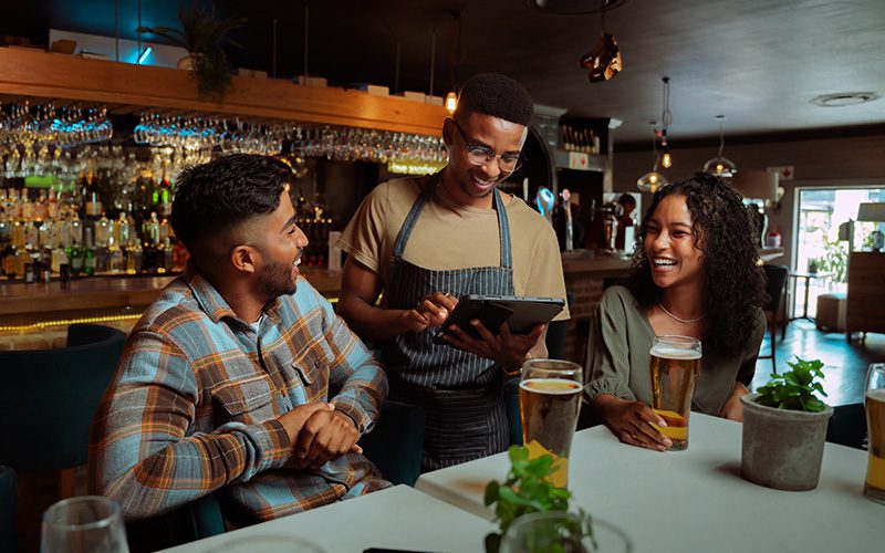 A server taking an order from a couple in a bar.
