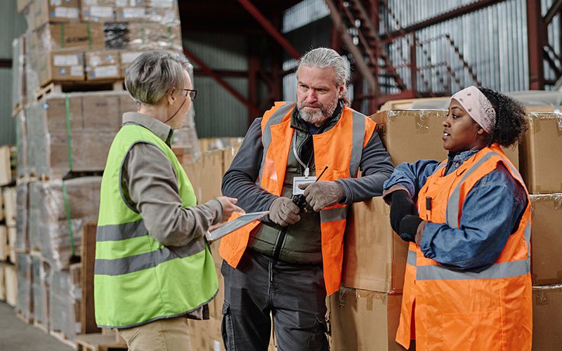 A warehouse manager talking to two warehouse workers
