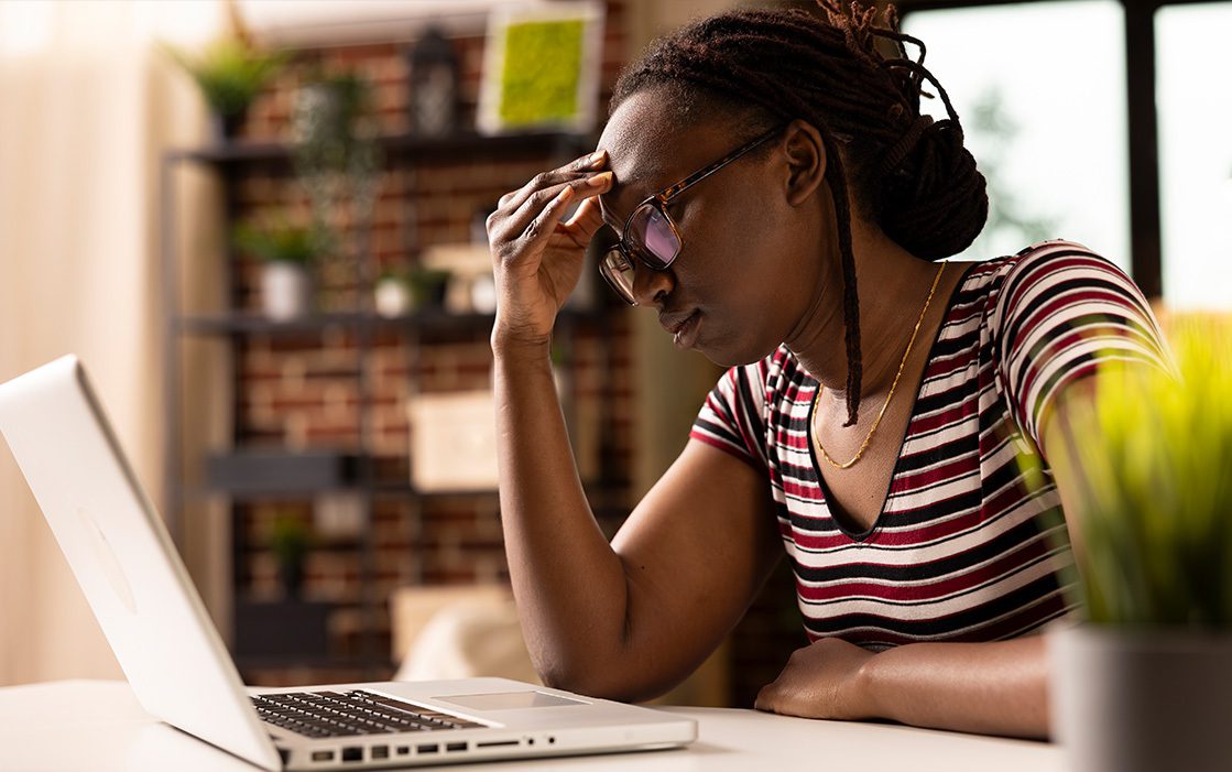 Image shows a woman working from home and looking stressed.
