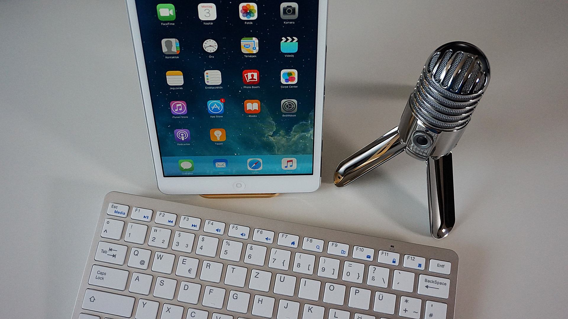 Image shows a keyboard, iPad and microphone on a desk.