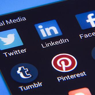 Image shows a close-up of a phone screen which has various social media app thumbnails on the screen.