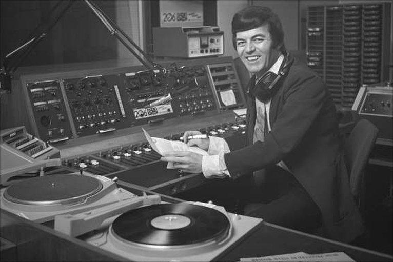 A black and white photo of a youngTony Blackburn in a radio studio.